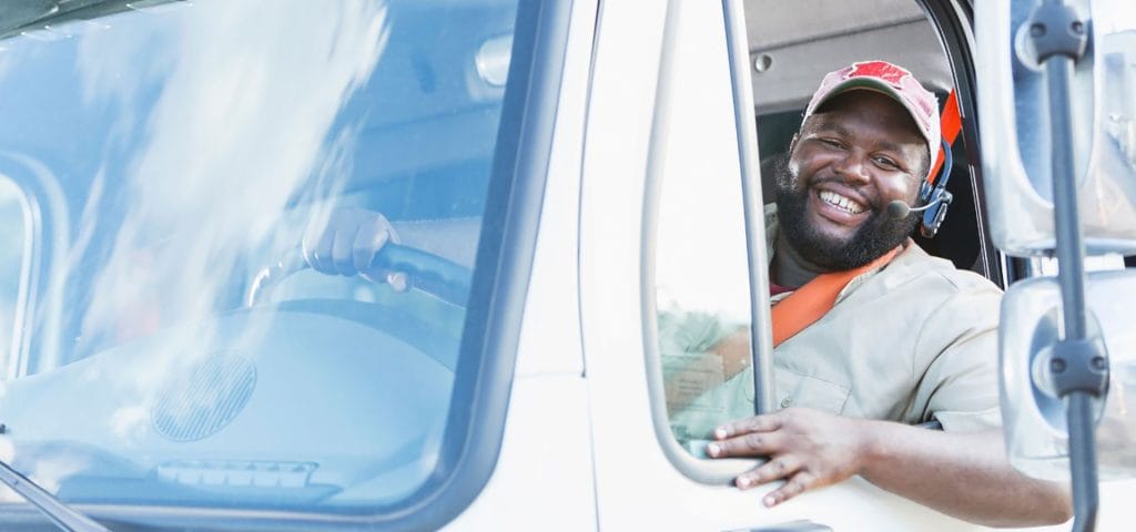 CDL driver smiling in truck cab - CDL vision requirements for DOT physical